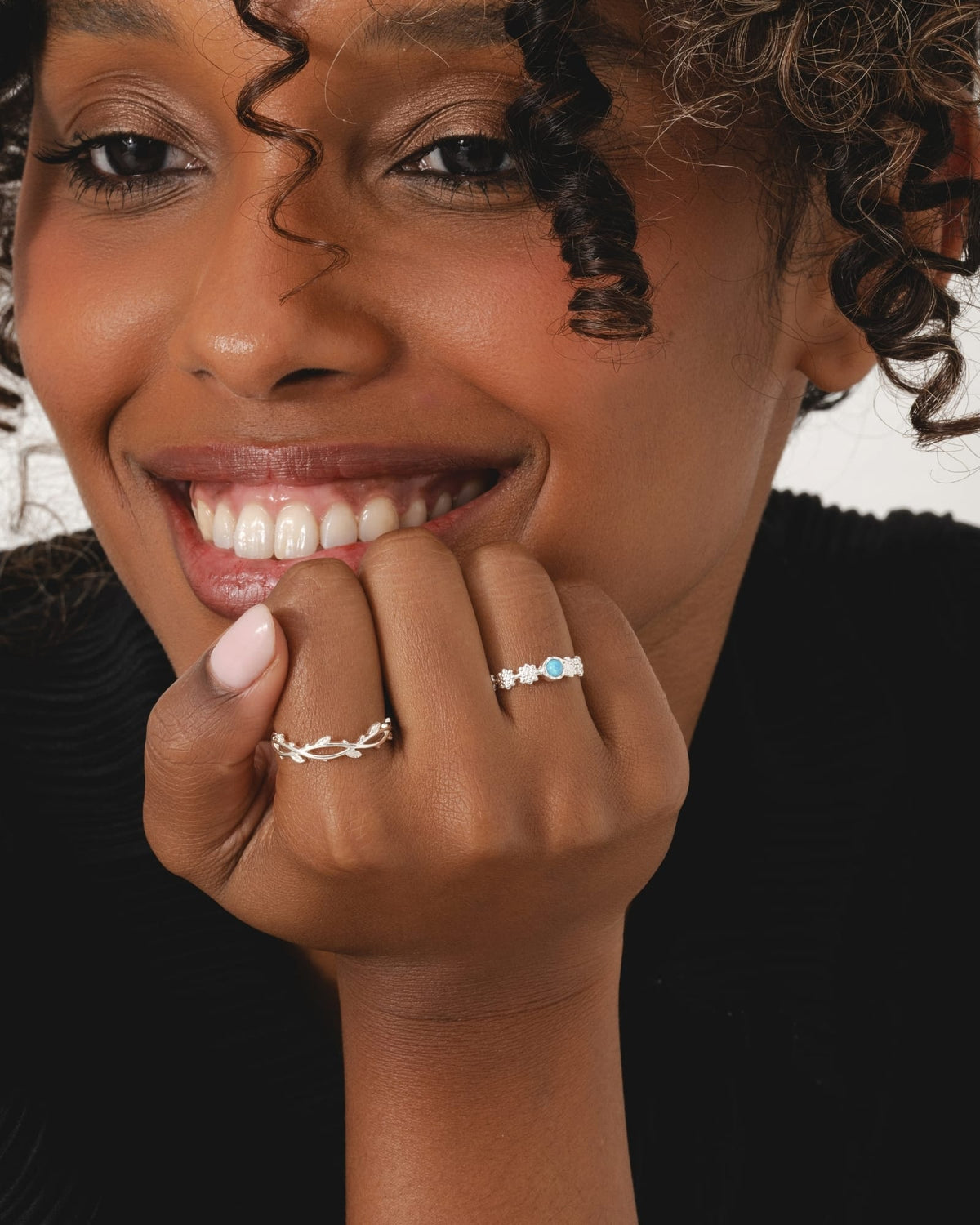 Sterling silver daisy chain ring featuring a bright blue cultured opal, worn on a woman's finger.