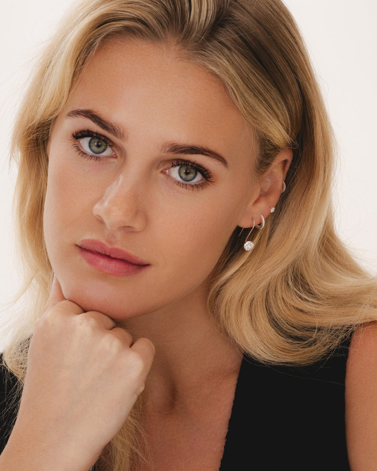 Model wearing delicate sterling silver huggie hoop earrings featuring sparkling cubic zirconia stones.