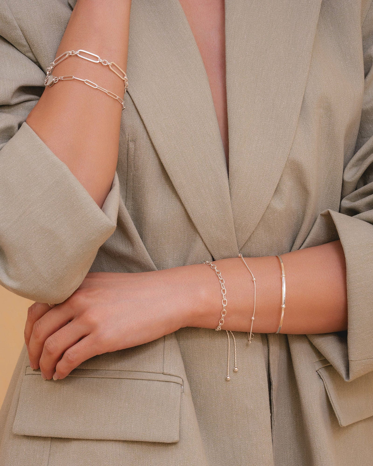 Sterling silver snake chain bracelet with silver bobble accents, worn stacked with other silver chains on a model's wrist.