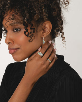 Sterling silver drop earrings featuring iridescent green and blue paua shell in an elegant leaf shape.