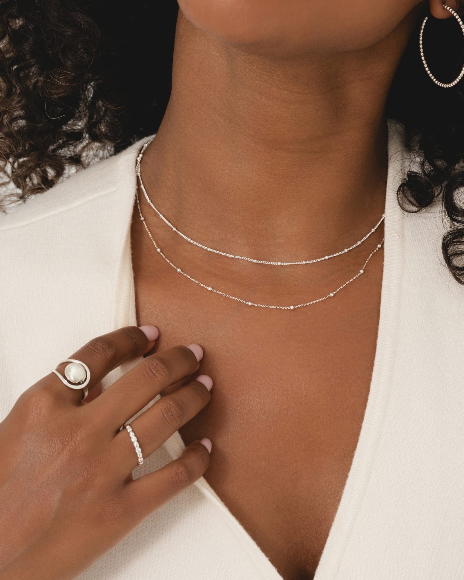 Sterling silver bobble station chain layered on a model, featuring a delicate curb chain with small silver balls.