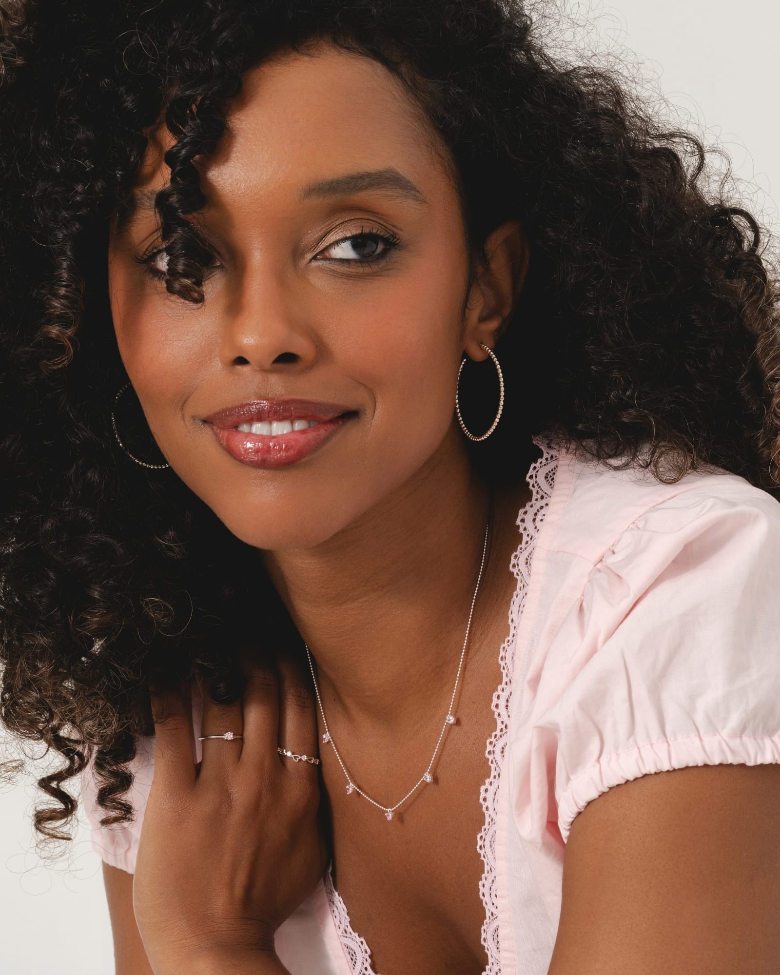 Slim sterling silver ring with a claw-set pale pink cubic zirconia solitaire on a woman's finger.