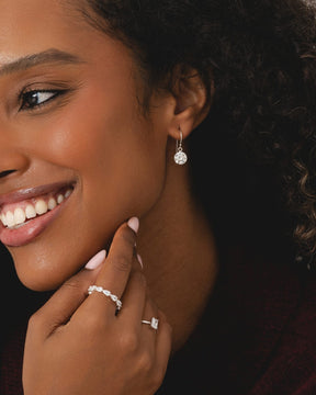 Sterling silver eternity band with inline pear-shaped cubic zirconia stones worn on a finger.