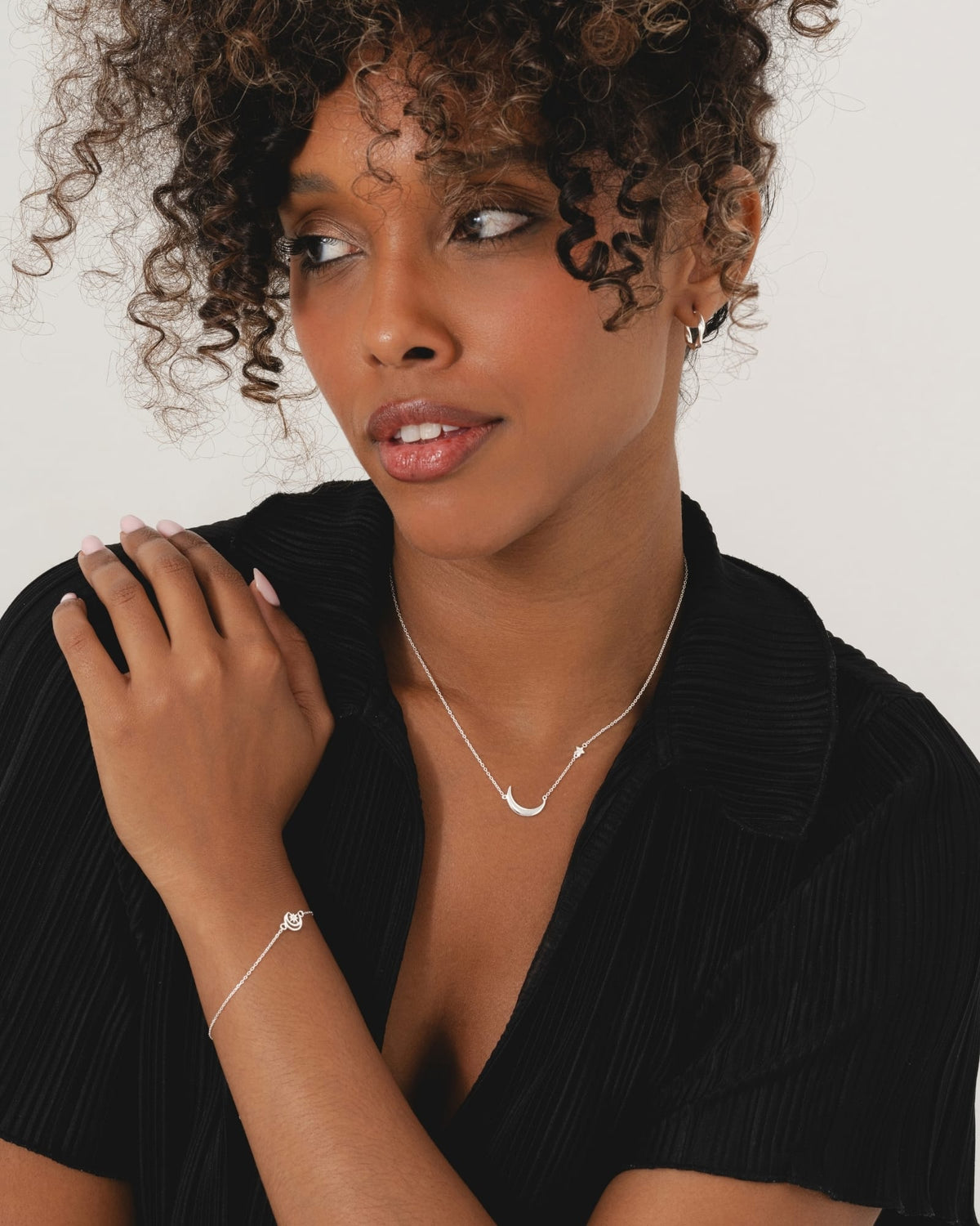 Model wearing a sterling silver necklace with an asymmetric moon and star charm design against a black top.