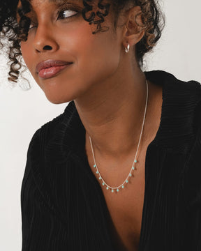 Sterling silver necklace featuring delicate chain with dangling faceted aqua amazonite beads worn by a woman.