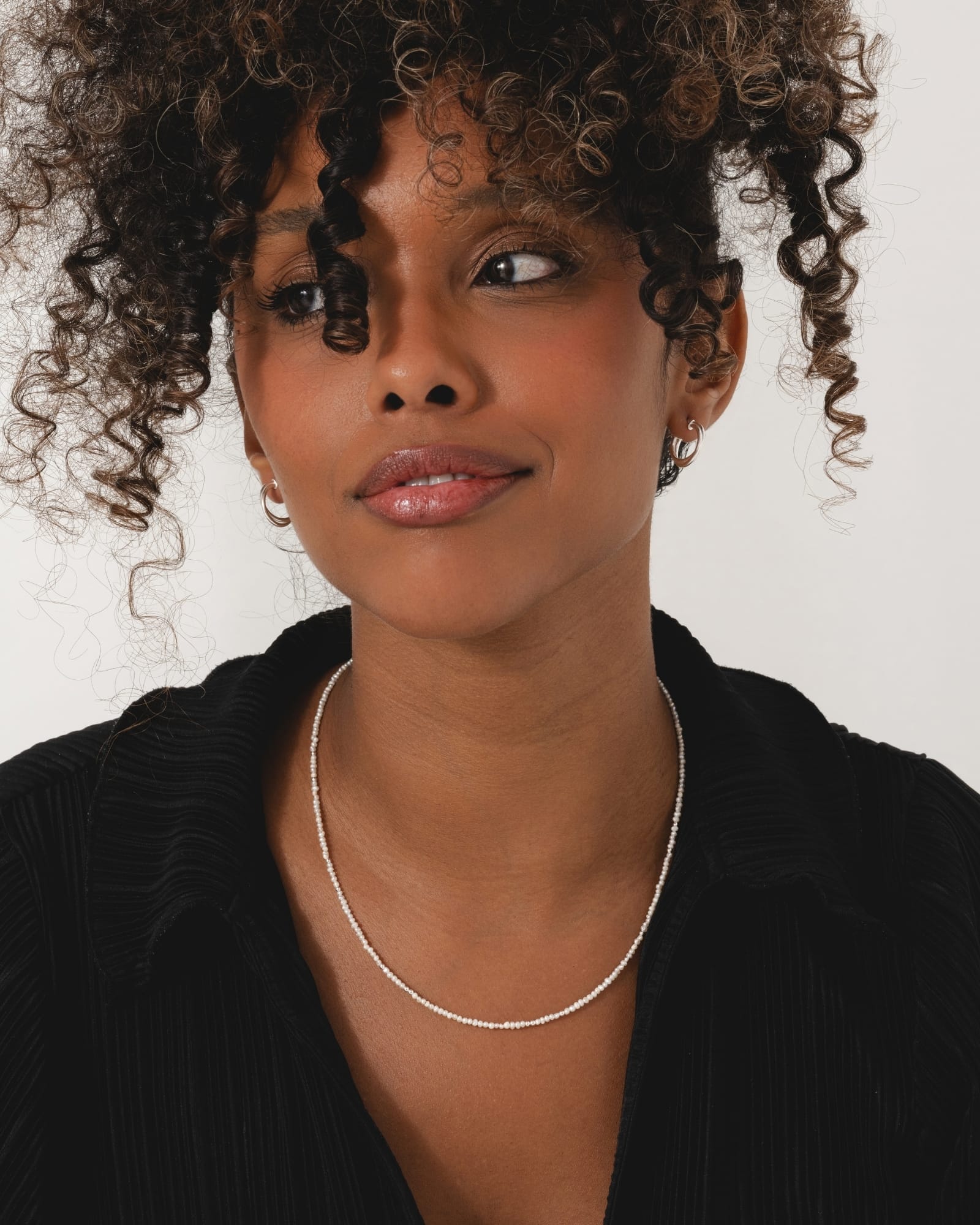 Delicate necklace featuring tiny white freshwater pearls and polished sterling silver beads worn by a woman.