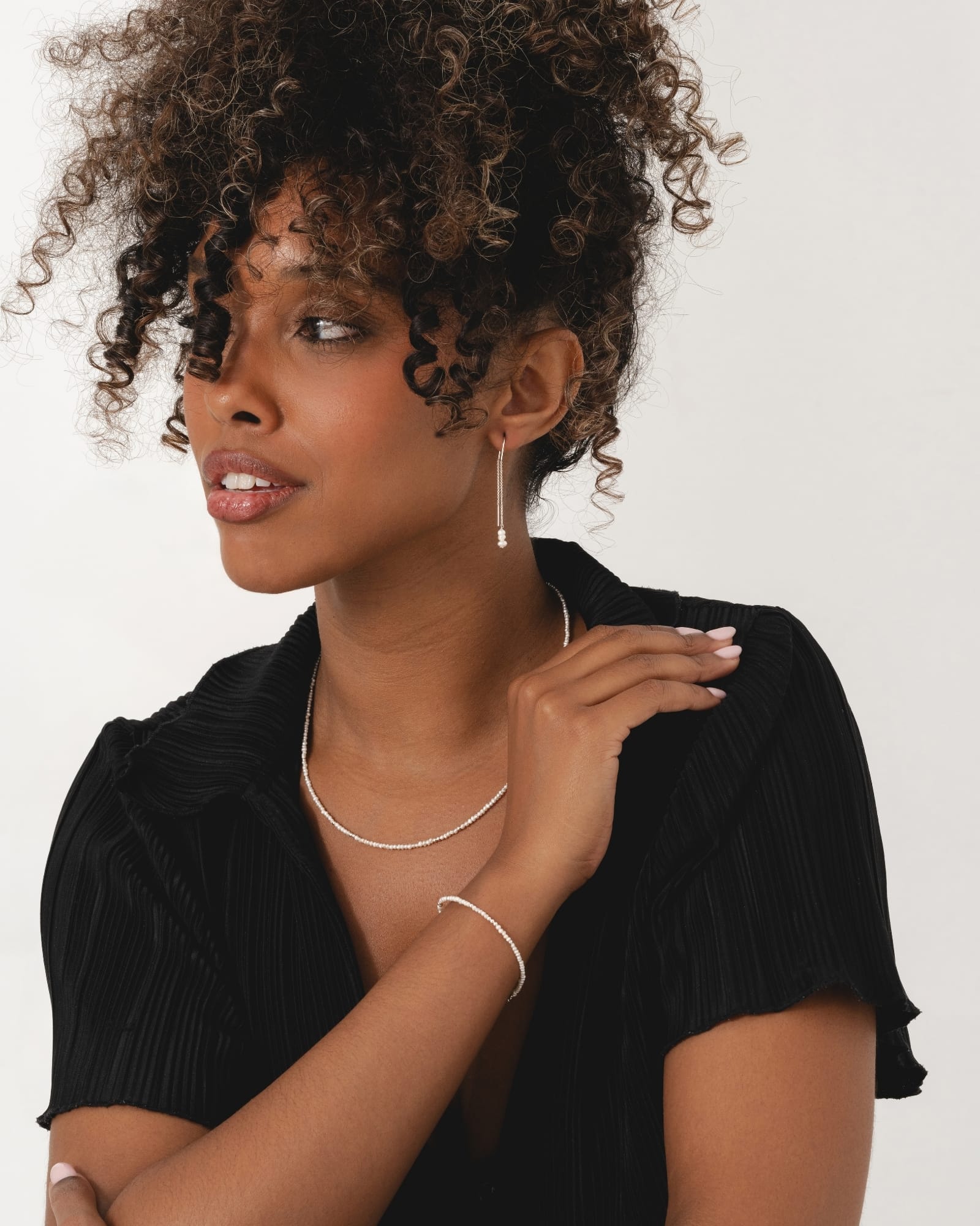 Model wearing sterling silver pull-through earrings with a delicate chain and a cluster of small freshwater pearls.