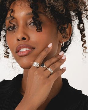 Sterling silver oval ring with a black onyx stone and oxidized rope edge detail worn on a finger.