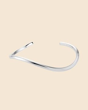 Polished sterling silver cuff bangle with a sleek, minimalist wavy design on a light background.
