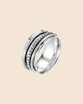 Sterling silver spinning ring with a wide base band and textured beaded outer bands on a cream background.